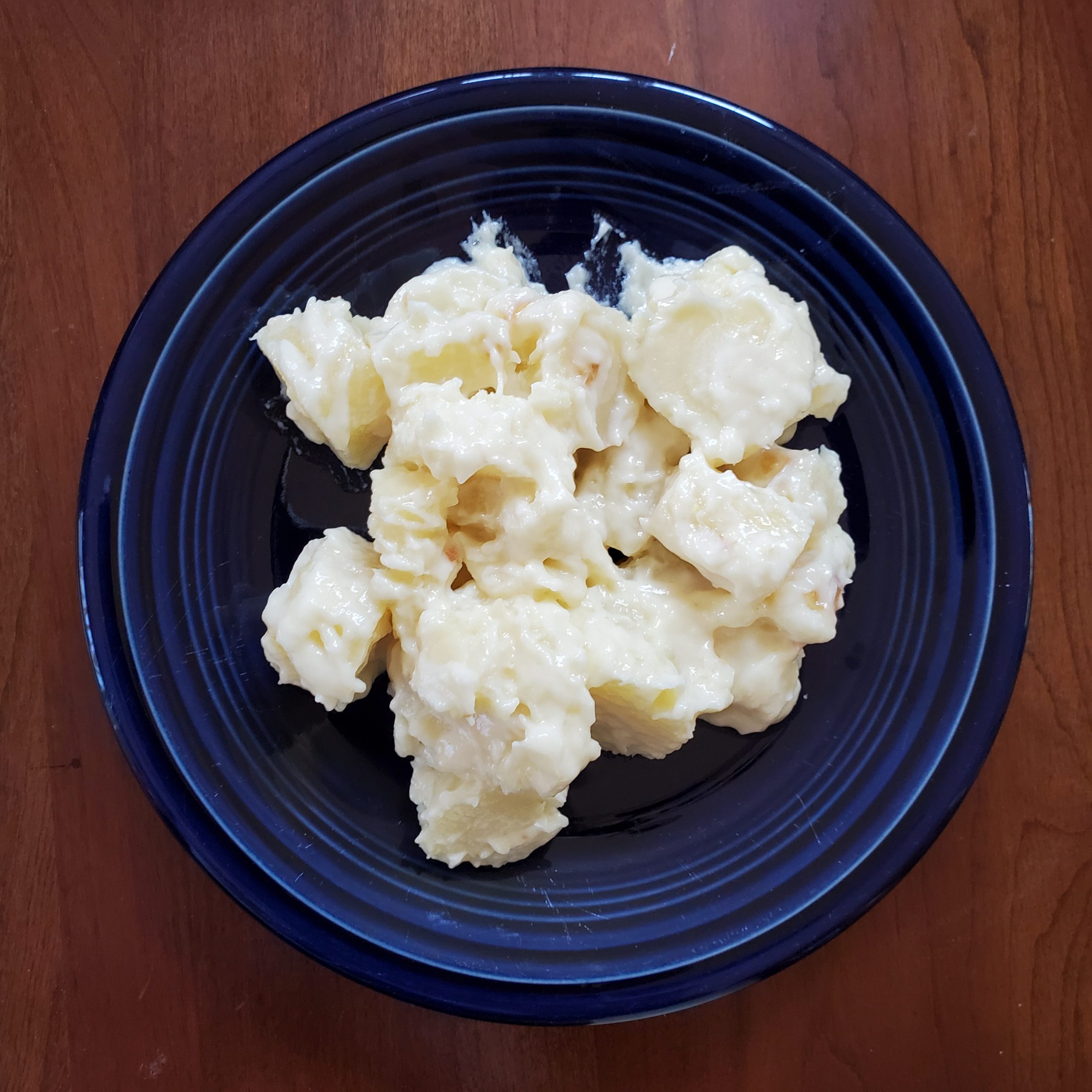 Stewed parsnips in a blue bowl on a brown table.