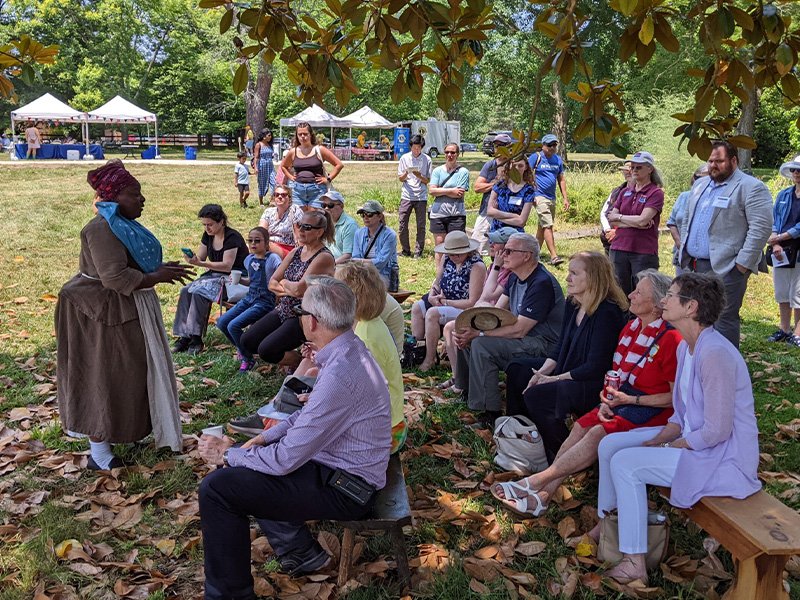 Living history program at Gunston Hall with interpreter speaking to a seated audience outdoors